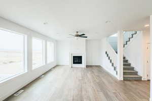 Unfurnished living room with visible vents, baseboards, light wood-style flooring, stairway, and a fireplace