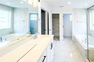 Full bathroom with a garden tub, marble finish floor, a spacious closet, vanity, and recessed lighting