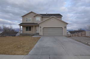 Traditional home with concrete driveway, covered porch, fence, and stucco siding