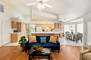 Living room with light wood-type flooring, visible vents, and vaulted ceiling