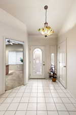 Foyer entrance with light tile patterned floors and vaulted ceiling