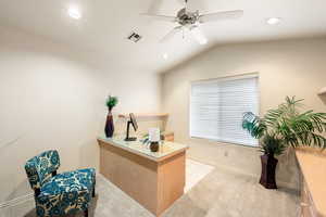 Office space featuring lofted ceiling, visible vents, light carpet, ceiling fan, and baseboards