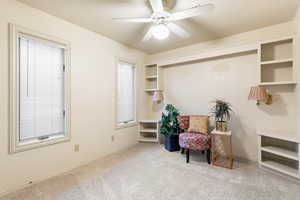 Living area featuring baseboards, a ceiling fan, and light colored carpet