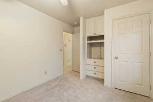 Unfurnished bedroom with light carpet and baseboards