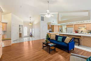 Living area with high vaulted ceiling, visible vents, light wood-style flooring, and a ceiling fan