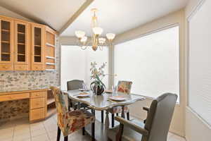 Dining area with lofted ceiling, wallpapered walls, baseboards, and light tile patterned floors