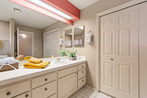 Bathroom with a closet, visible vents, a ceiling fan, vanity, and tile patterned floors