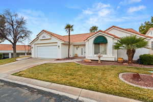 Mediterranean / spanish-style house featuring an attached garage, a front yard, concrete driveway, and a tiled roof