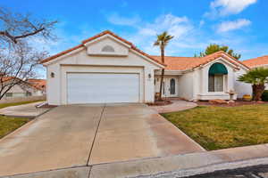 Mediterranean / spanish house with an attached garage, a tile roof, driveway, stucco siding, and a front yard