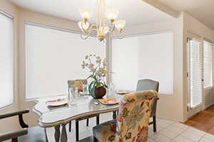 Dining area featuring a chandelier, light tile patterned flooring, and baseboards