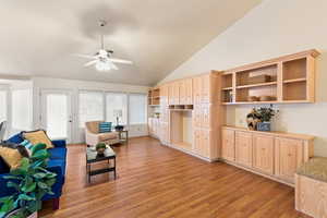 Living room with a ceiling fan, light wood-type flooring, and high vaulted ceiling