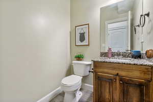 Half bath featuring baseboards, vanity, and toilet