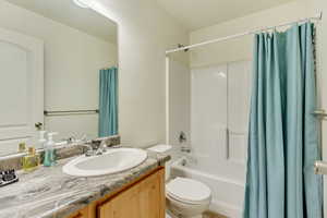 Bathroom featuring toilet, shower / bath combination with curtain, and vanity