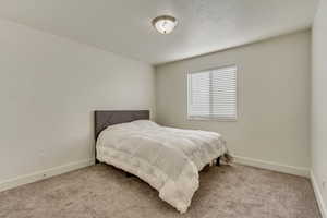 Bedroom featuring light carpet and baseboards