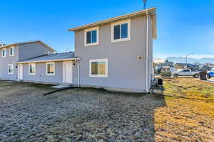 Rear view of property featuring central air condition unit, a mountain view, and stucco siding