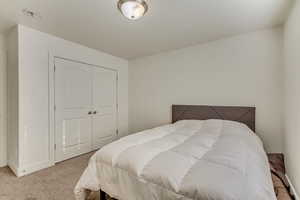 Bedroom with light carpet and a closet