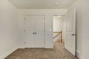 Unfurnished bedroom with light carpet, visible vents, baseboards, and a closet