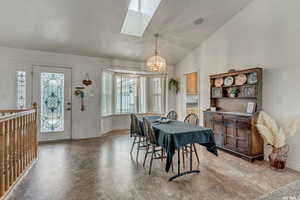 Dining space with lofted ceiling with skylight, baseboards, and an inviting chandelier