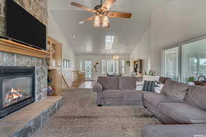 Living room with a skylight, high vaulted ceiling, and a stone fireplace