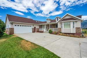 View of front of property featuring a garage, brick siding, concrete driveway, a porch, and a front yard