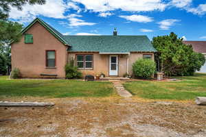 View of front of home with a front yard, roof with shingles, a chimney, and stucco siding