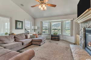 Living area featuring carpet floors, a healthy amount of sunlight, a fireplace, and lofted ceiling