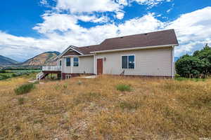 Back of property featuring a deck with mountain view, a shingled roof, and stairway