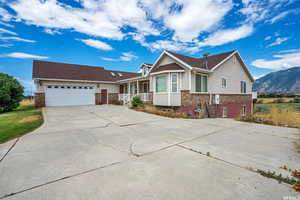 Ranch-style home featuring a garage, concrete driveway, a porch, and a mountain view