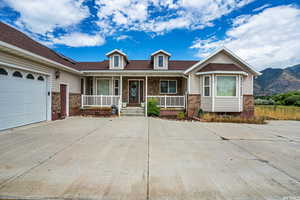 View of front of house featuring driveway, an attached garage, covered porch, a mountain view, and brick siding