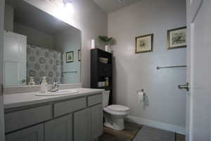 Bathroom featuring hardwood / wood-style floors, toilet, curtained shower, and vanity