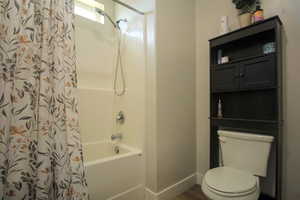 Bathroom featuring shower / tub combo with curtain, toilet, and hardwood / wood-style floors