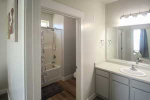 Full bathroom featuring hardwood / wood-style flooring, shower / bath combination with curtain, vanity, and toilet