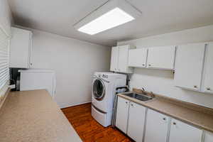 Laundry room with cabinet space, dark wood finished floors, and a sink