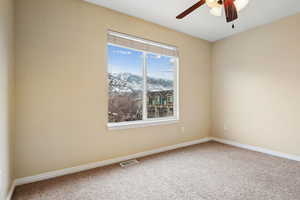 Carpeted empty room featuring a mountain view and ceiling fan