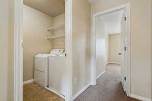 Laundry area featuring washer and clothes dryer and light colored carpet