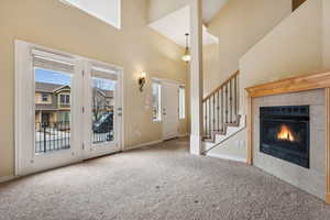 Unfurnished living room featuring a fireplace, a high ceiling, light colored carpet, and plenty of natural light