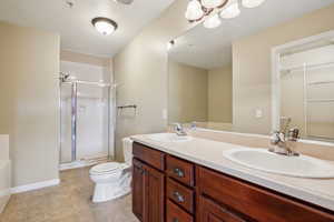 Bathroom featuring toilet, tile patterned flooring, vanity, and walk in shower