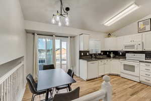 Kitchen featuring white appliances, white cabinetry, pendant lighting, and a sink