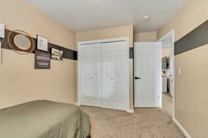 Bedroom with baseboards, a closet, and light colored carpet