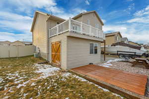 Snow covered rear of property featuring cooling unit, a gate, fence, and a wooden deck