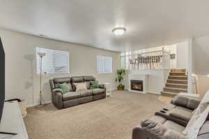 Living area with baseboards, stairs, visible vents, and light colored carpet