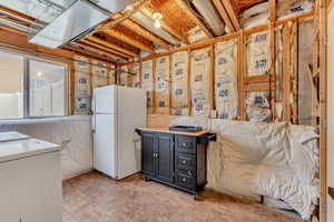 Basement with freestanding refrigerator and washer / clothes dryer