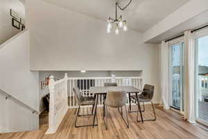 Dining area with light wood-style flooring, baseboards, and a notable chandelier