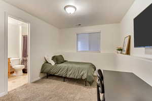 Bedroom with light carpet, connected bathroom, and visible vents