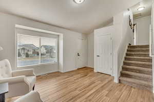 Unfurnished room with light wood-type flooring, visible vents, baseboards, and lofted ceiling