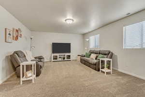 Living room with carpet floors, visible vents, and baseboards