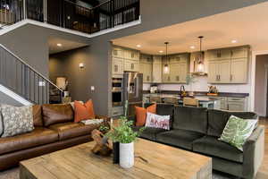 Living area featuring recessed lighting, wood finished floors, a high ceiling, and stairs