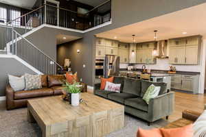 Living room featuring baseboards, a high ceiling, light wood finished floors, and stairs