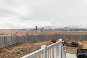 View of yard with a rural view, fence, and a mountain view