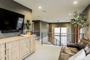 Living area featuring light carpet, visible vents, and recessed lighting